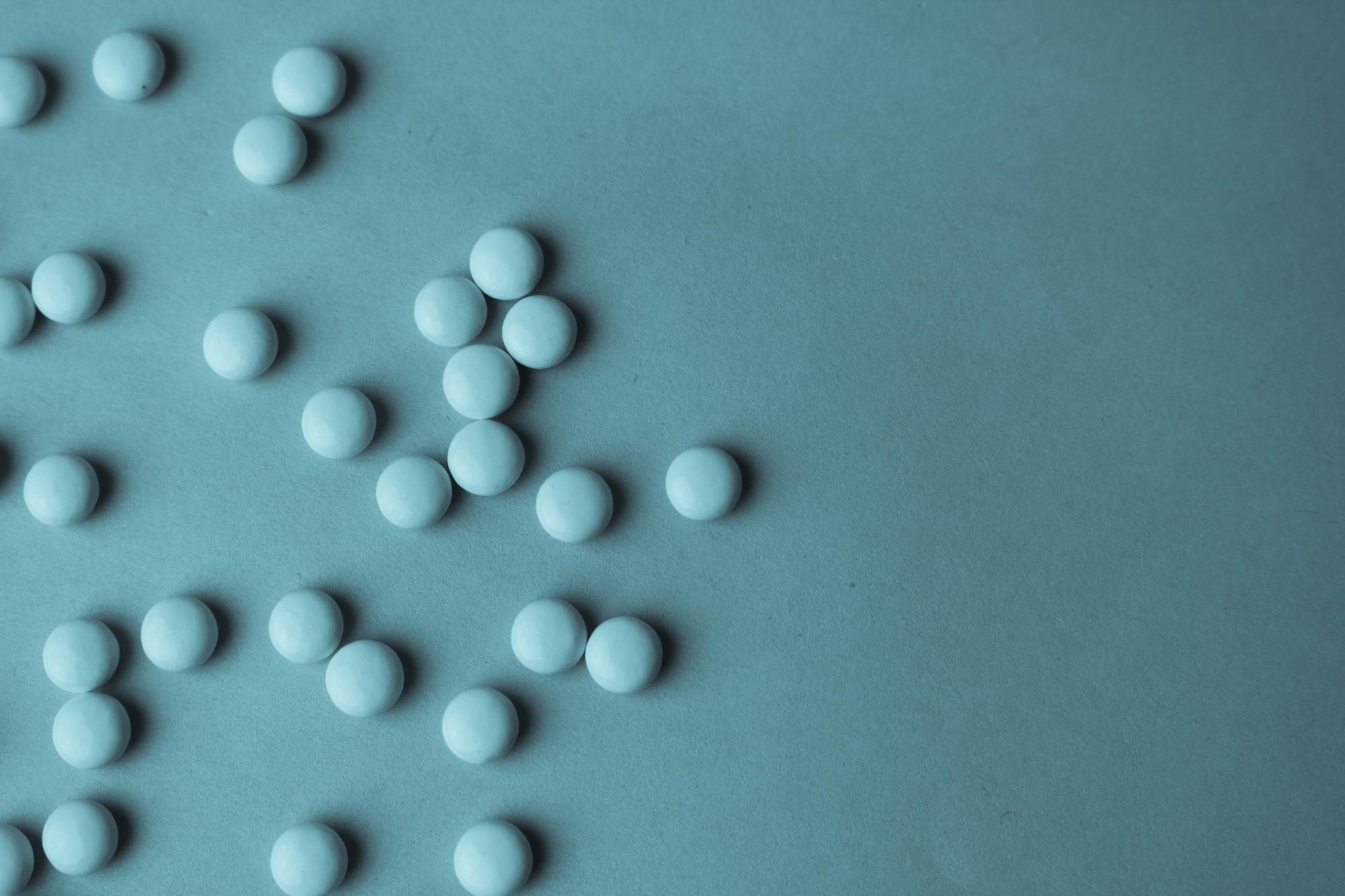 Three scientists wearing safety goggles and lab coats working with glassware and equipment in a laboratory.
