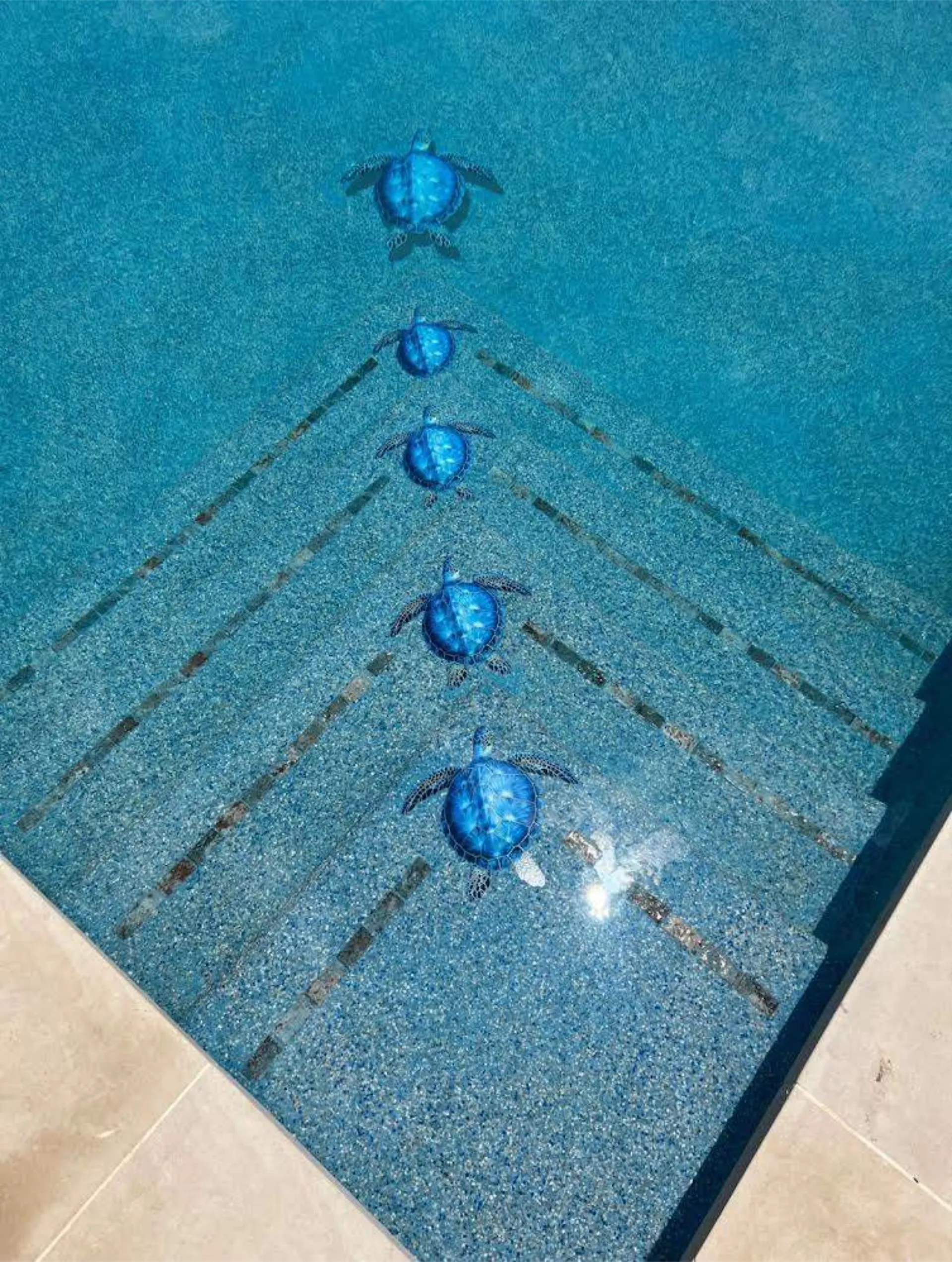 Blue ceramic sea turtle decorations arranged on the steps of a swimming pool.