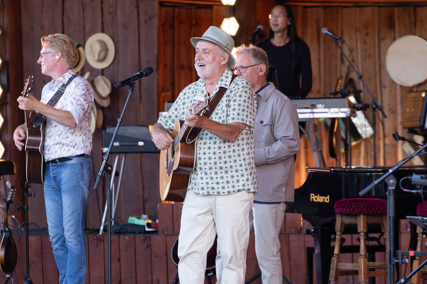 Fire mænd spiller musik på en træscene med guitarer og keyboard.