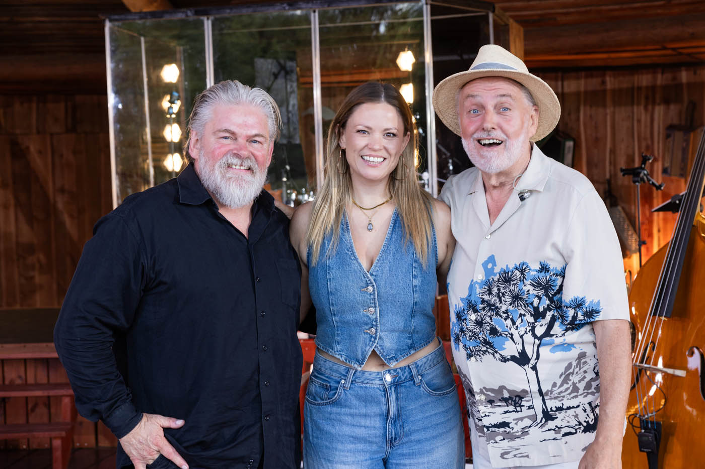 Helge Engelbrecht og Stig Rossenn står tæt sammen indendørs foran en kontrabas, med en mand i sort skjorte, en kvinde i denimvest og jeans og en mand med hat og mønstret skjorte.