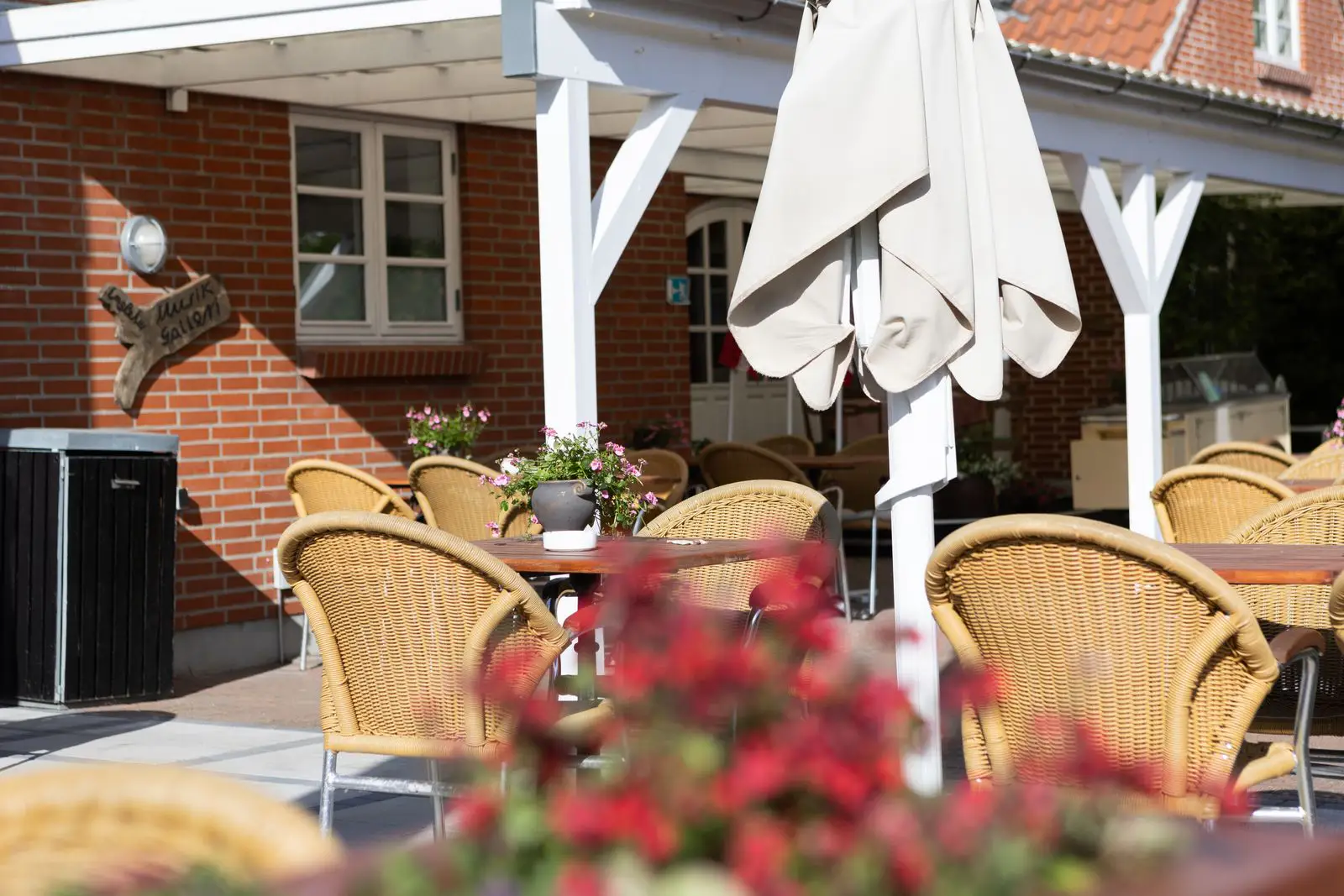 Bord dækket med hvid dug, grønne servietter, flere vinglas, lilla drikkeglas og bestik i et hyggeligt restaurantmiljø.