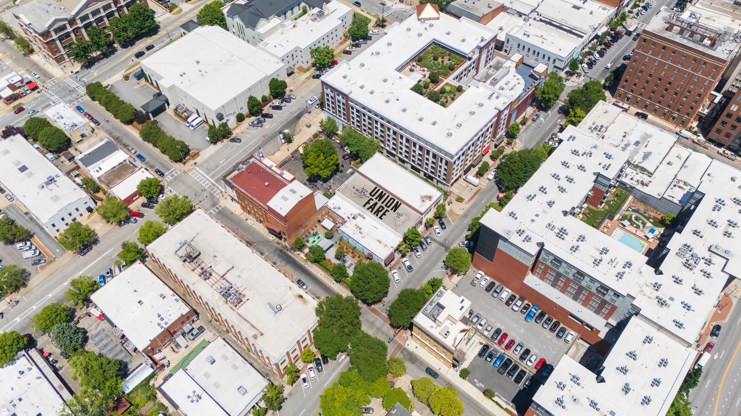 Aerial view of an urban block with buildings, trees, cars, and a white roof labeled Union Fare.