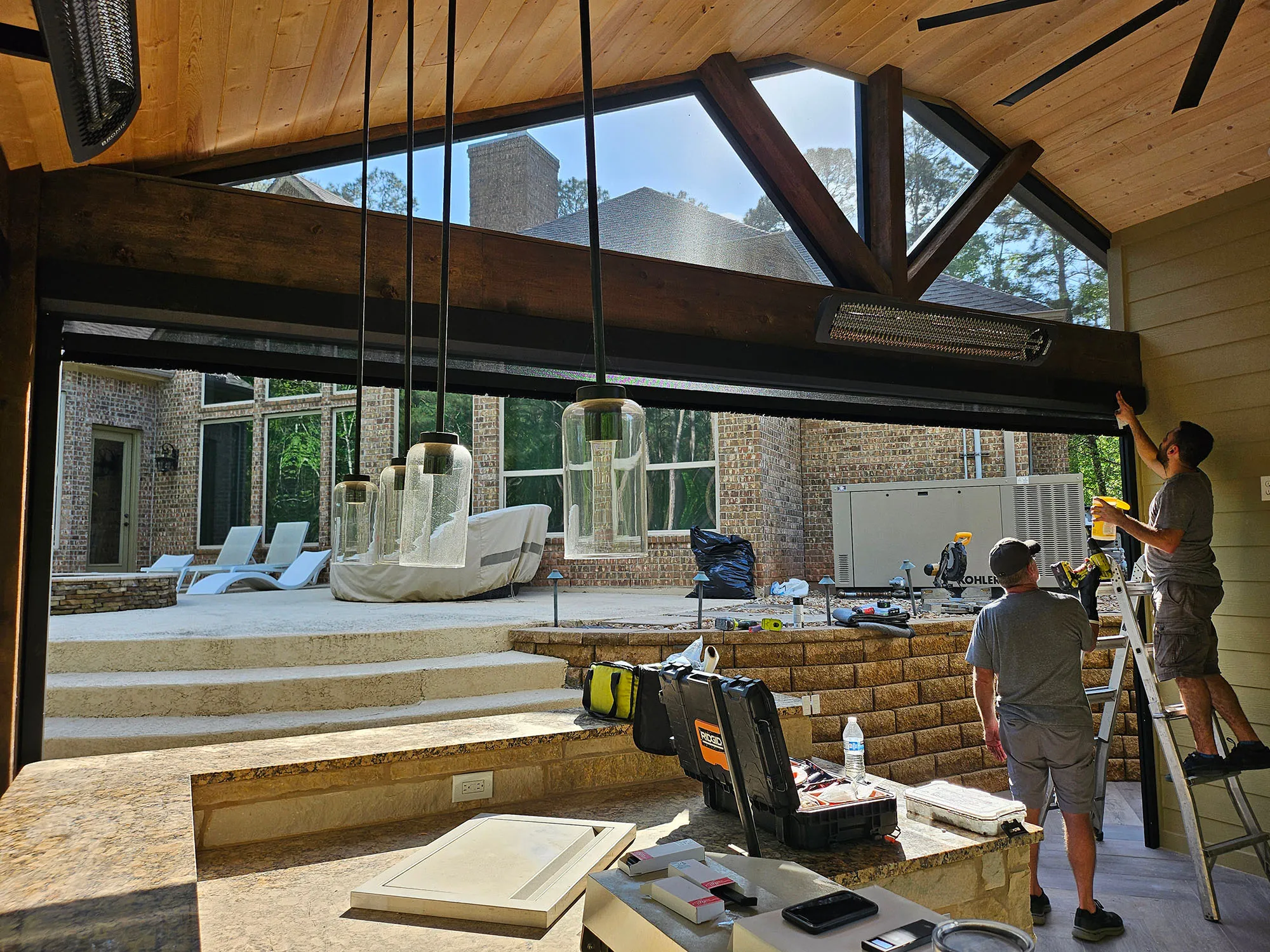 Workers installing fixtures in a modern home with large windows and outdoor area.