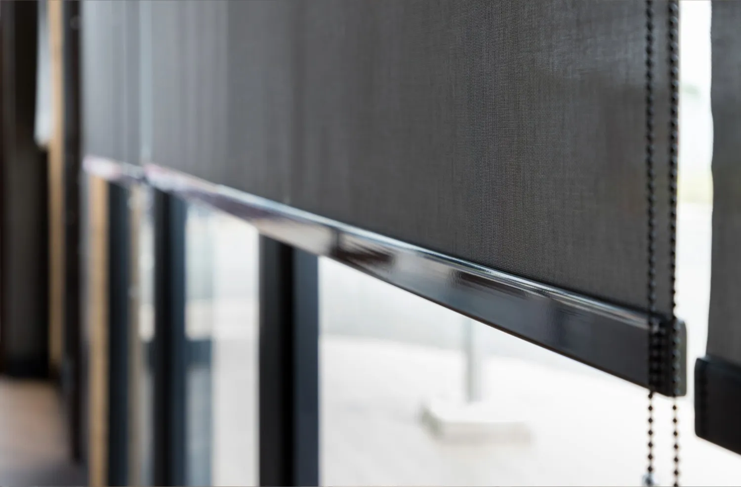 Close-up of a chain-operated roller blind partially covering a window.