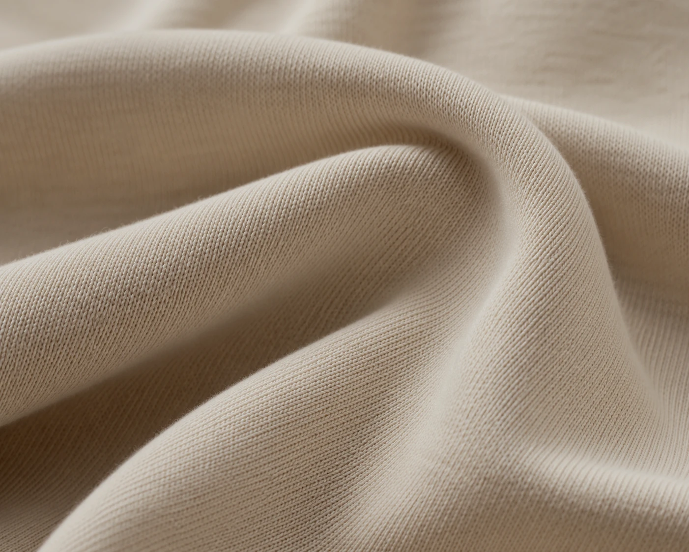 Close detail of a fine natural knit fabric in soft folds.
