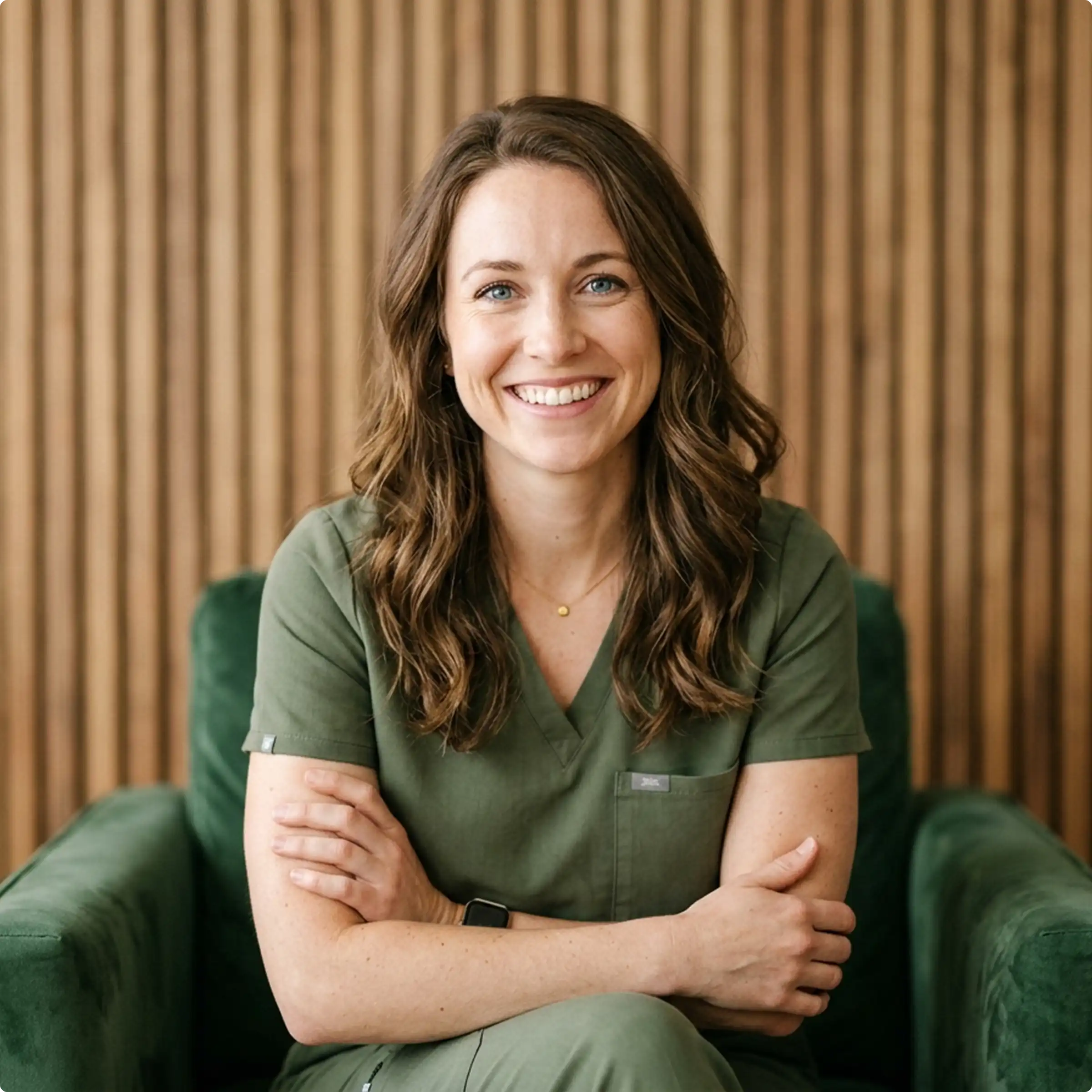 Smiling healthcare provider seated in front of a wood-paneled wall