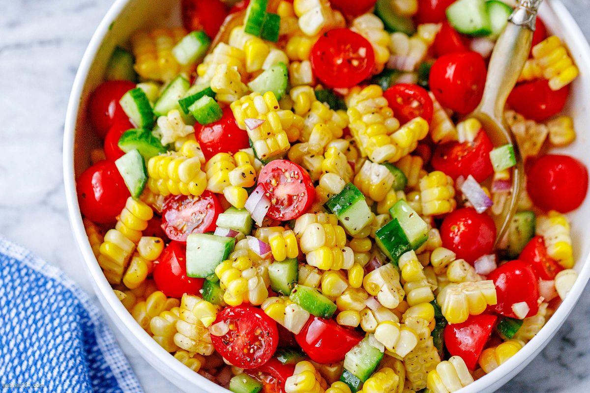 Tomato corn salad with cherry tomatoes, cucumber, and red onion in a bowl
