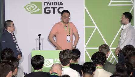 Three men standing on stage at NVIDIA GTC event with audience in front.