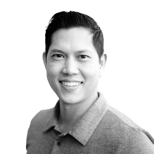 Smiling man with short dark hair wearing a collared shirt against a white background.