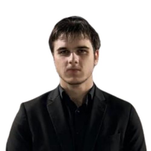 Young man with short dark hair wearing a black suit jacket and black shirt against white background.