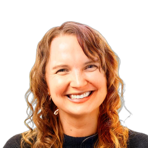 Smiling woman with curly hair wearing a dark sweater against a white background.
