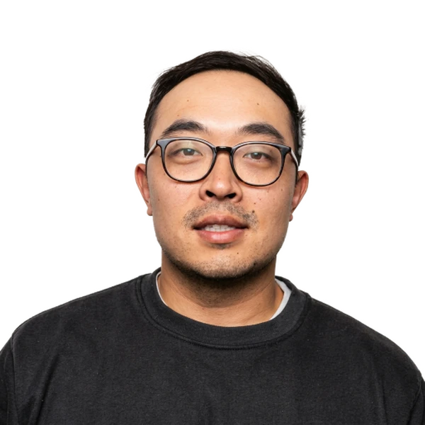 Headshot of a man with short dark hair and glasses, wearing a black t-shirt.