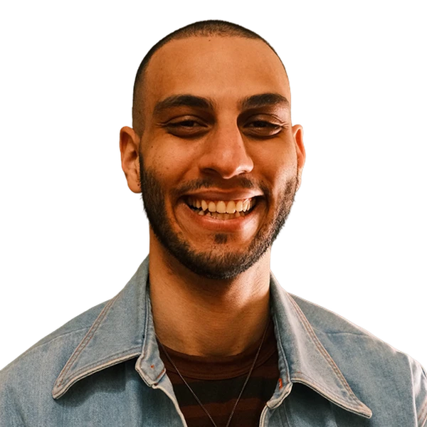 Headshot of a smiling man with a shaved head and beard, wearing a denim jacket.