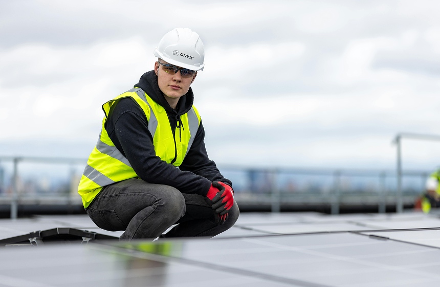 Onyx team member installing commercial rooftop solar panels on a city building for renewable energy generation.