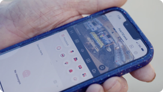Handholding a phone. The screen shows a dashboard with a video feed from a security camera.