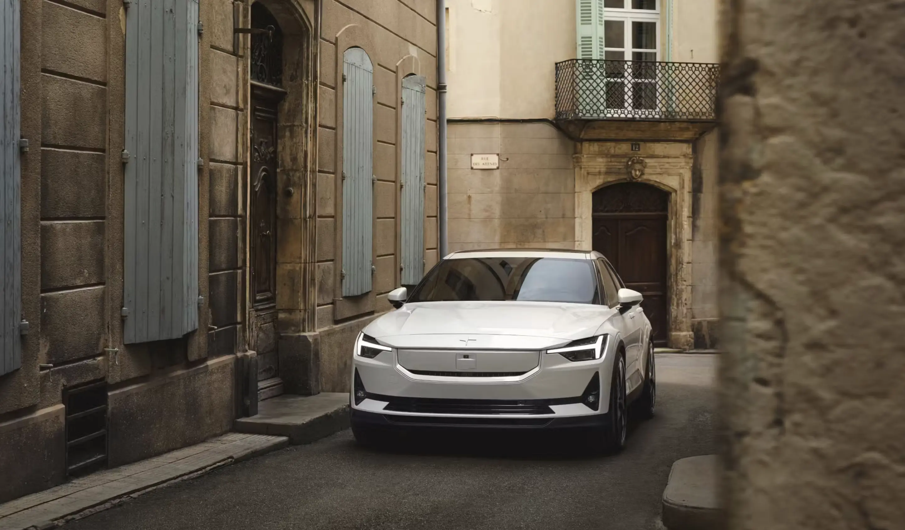 White Polestar vehicle parked on a European city street.
