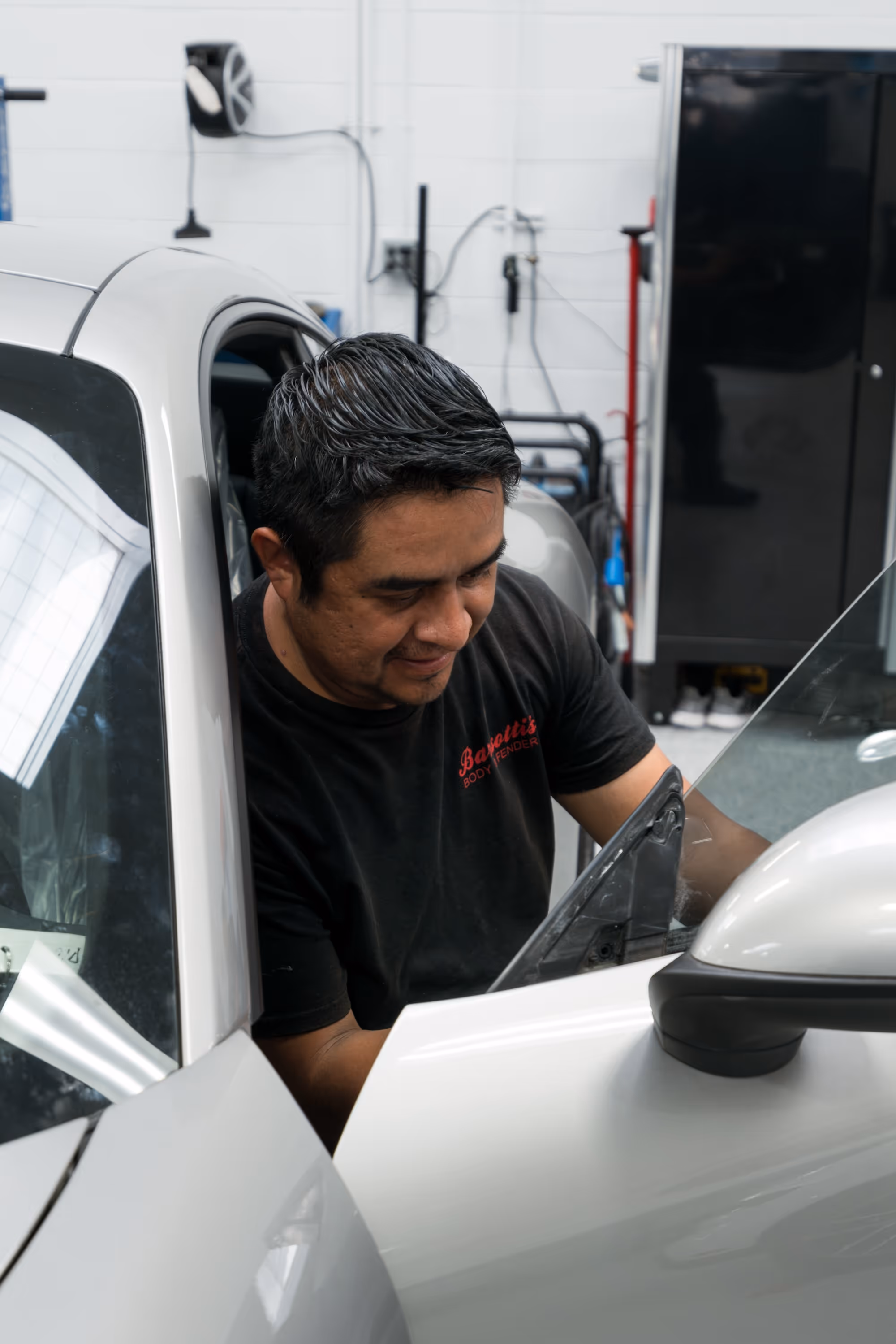 Smiling auto body technician working on the inside of a car door.