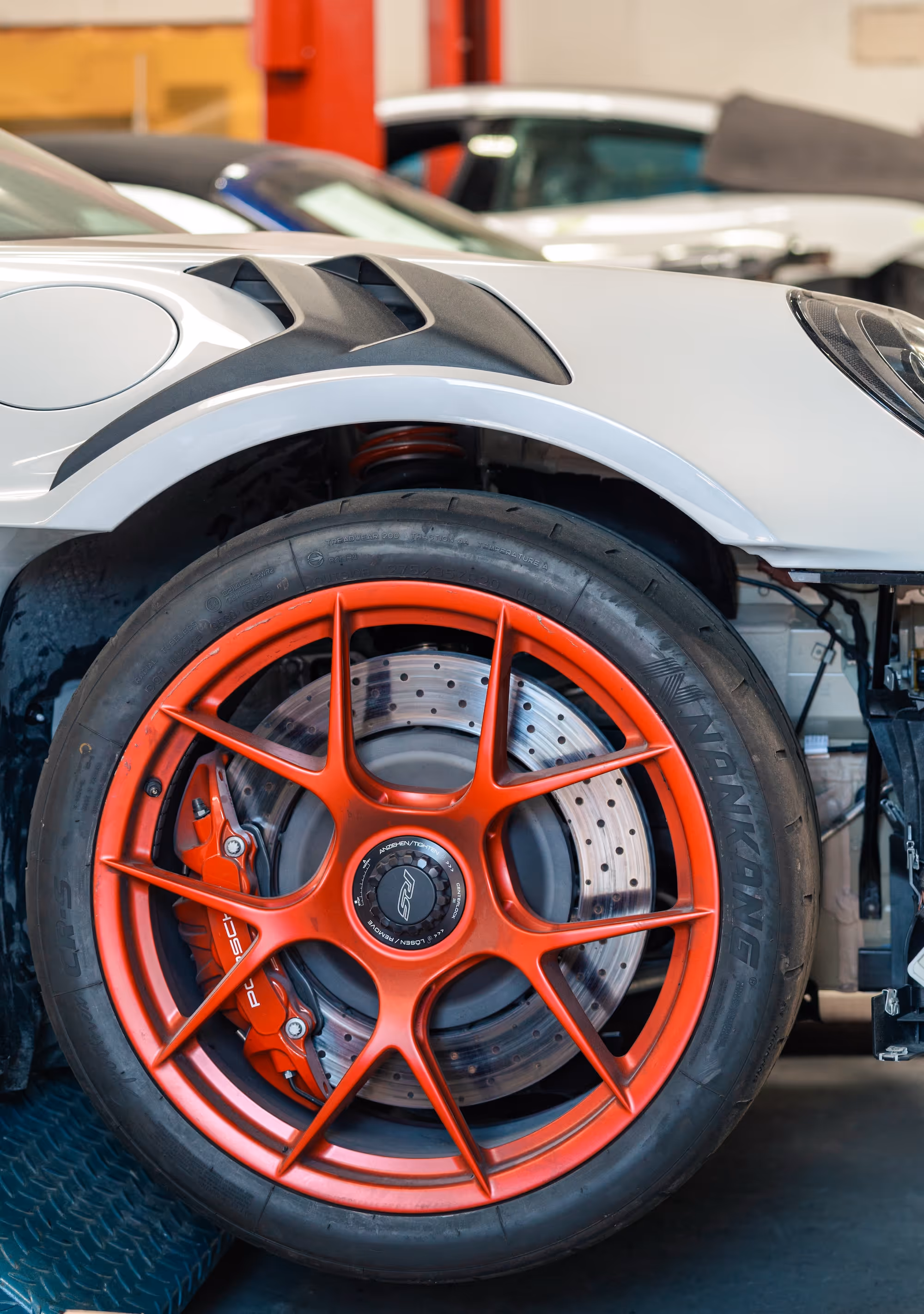 Red wheel and front fender of a car in the Barsotti's Body and Fender shop.