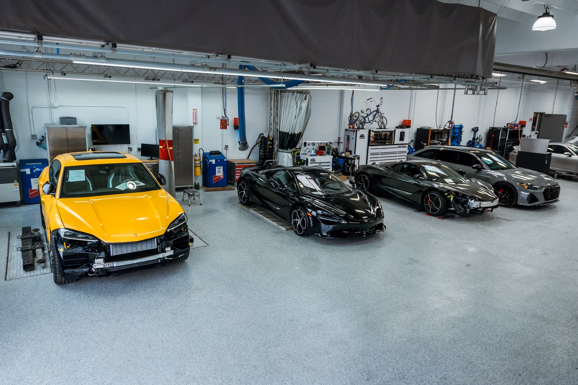 A lineup of Lamborghinis and other cars inside the shop at Barsotti's Body and Fender.