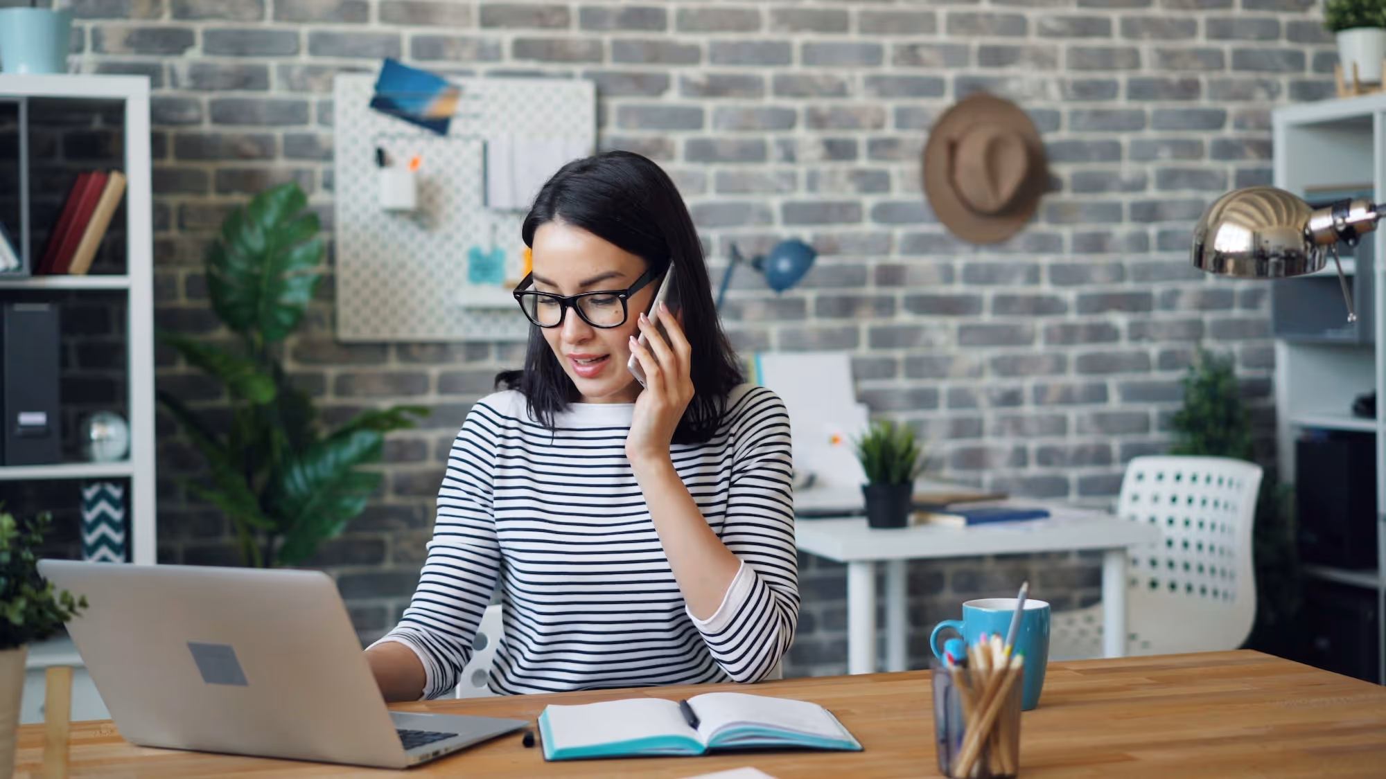 Smiling woman on the phone while user a computer.