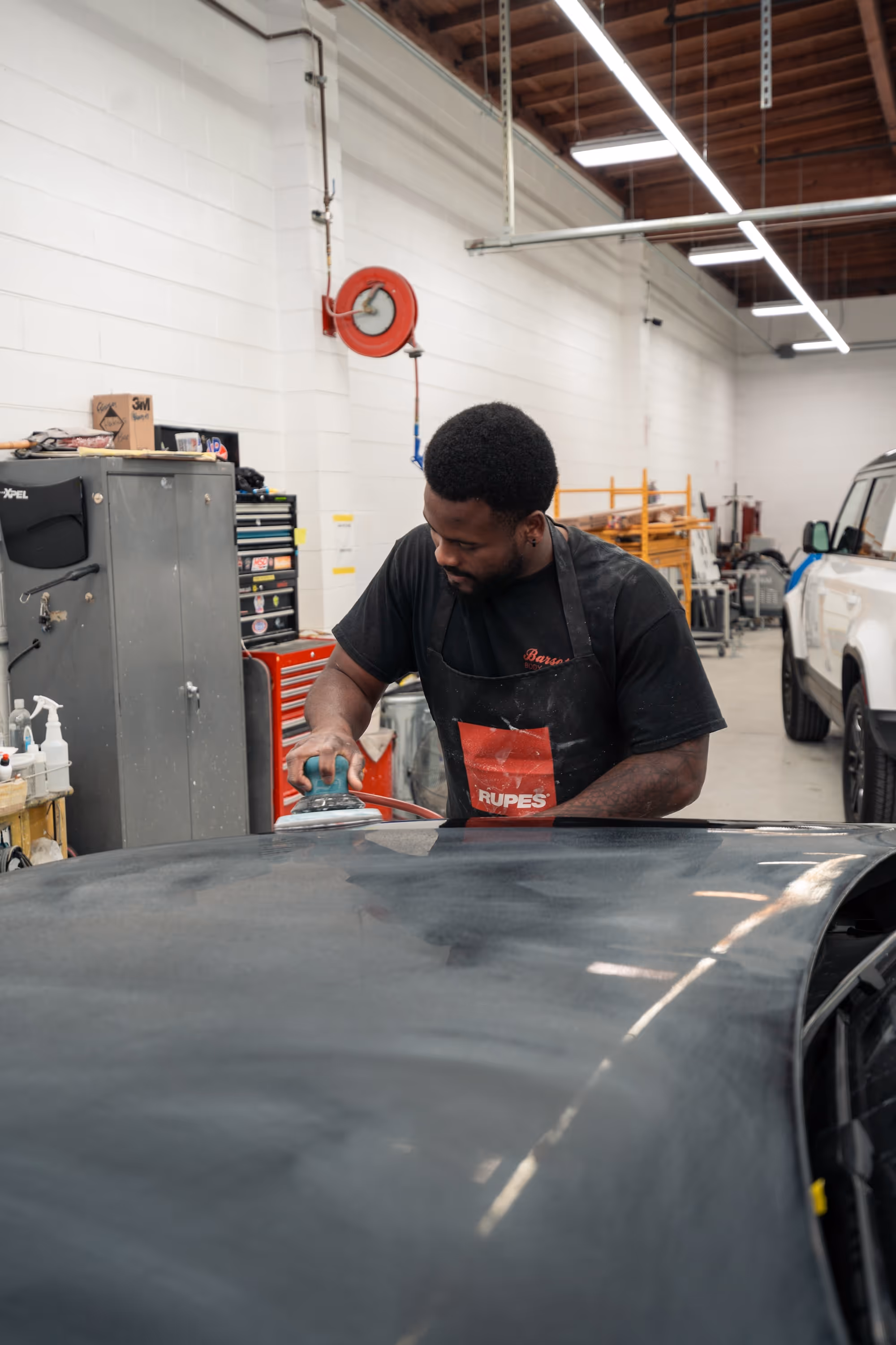 Collision repair expert buffing the hood of a car.