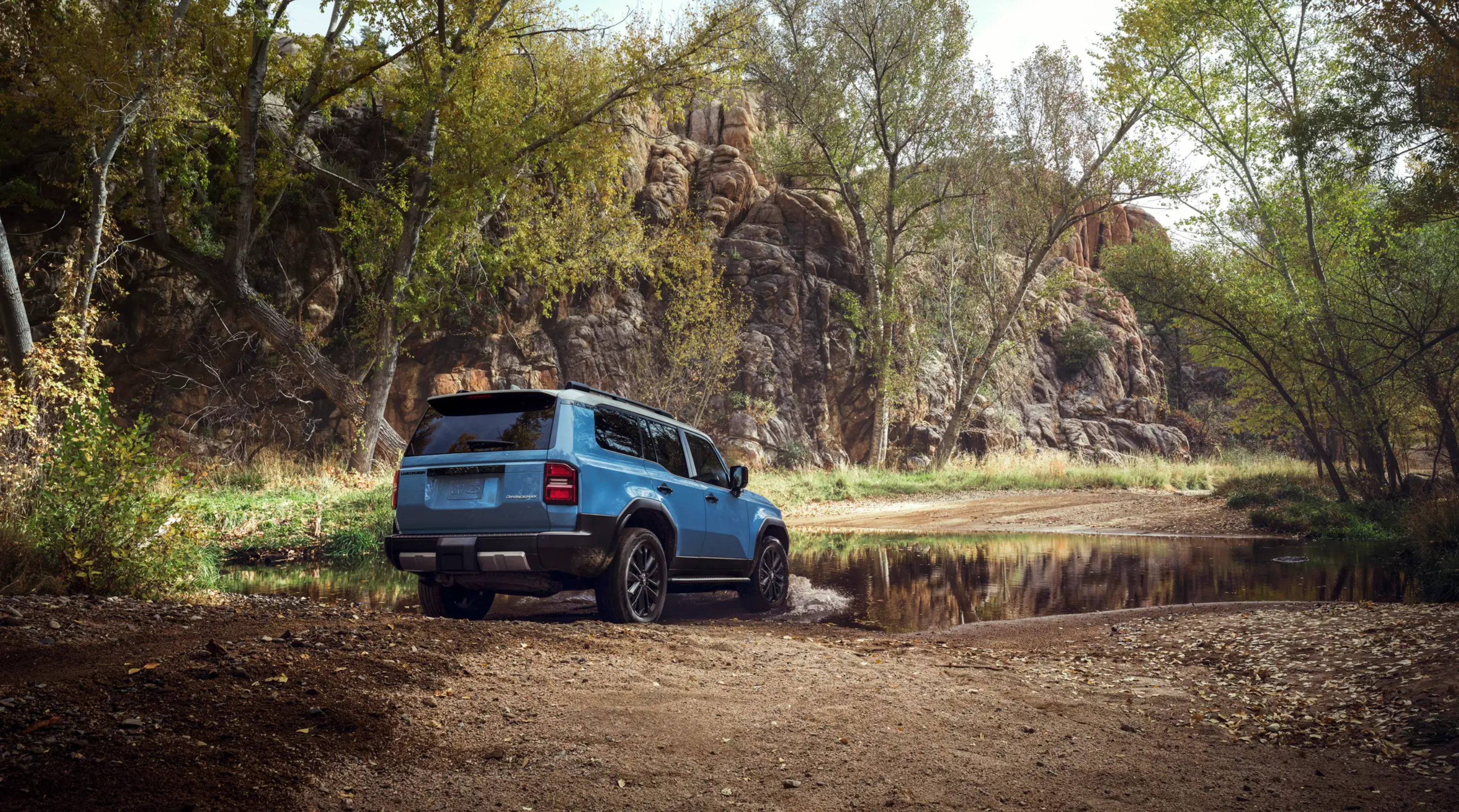 Blue Toyota Land Cruiser parked in front of a forest pond.