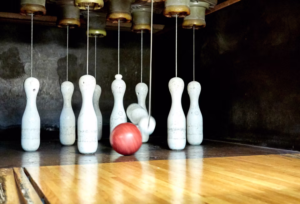 Rotierender Kegel und fallende weiße Kegel in einer klassischen Kegelbahn.