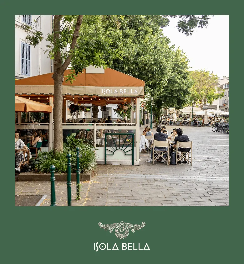 Terrasse de café Isola Bella avec des clients assis dehors sous des arbres, rue pavée animée.