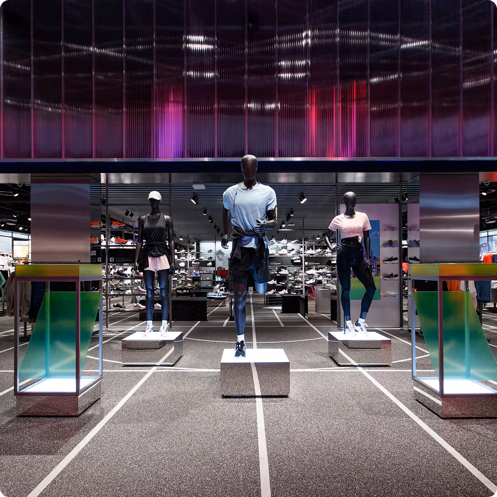 Athletic store display with three mannequins dressed in sportswear on platforms in front of shoe shelves