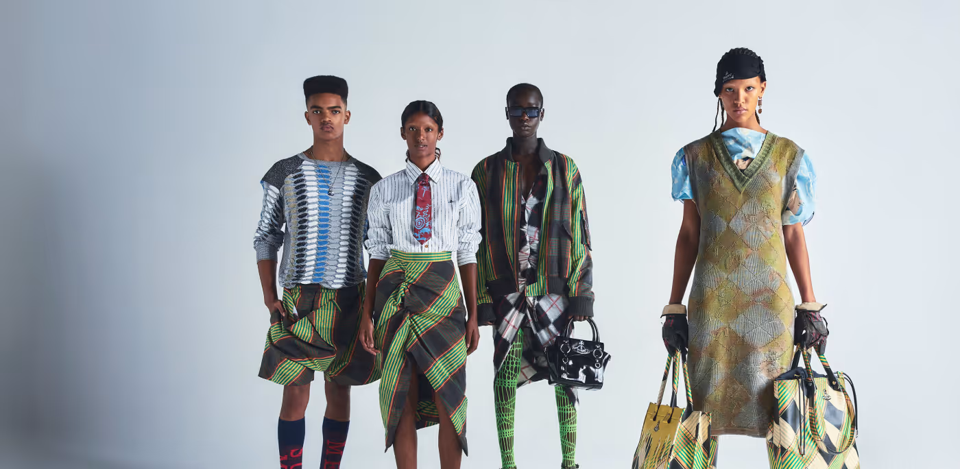 Four fashion models standing in colorful, patterned outfits against a plain background, featuring skirts, jackets, gloves, and large bags for Vivienne Westwood brand