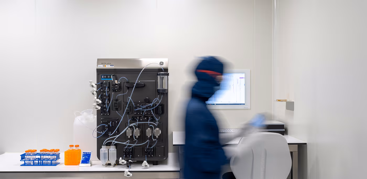 Laboratory technician in blue protective gear working beside advanced lab equipment and computer in a clean lab for Avenia brand