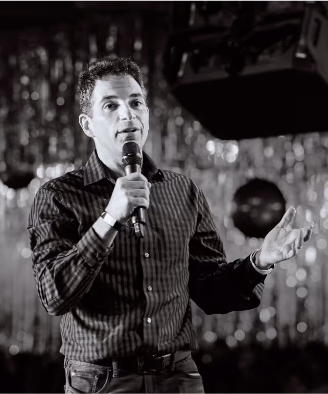 Astound Digital co-founder Ilya Vinogradsky in a checkered shirt holding a microphone and speaking on stage