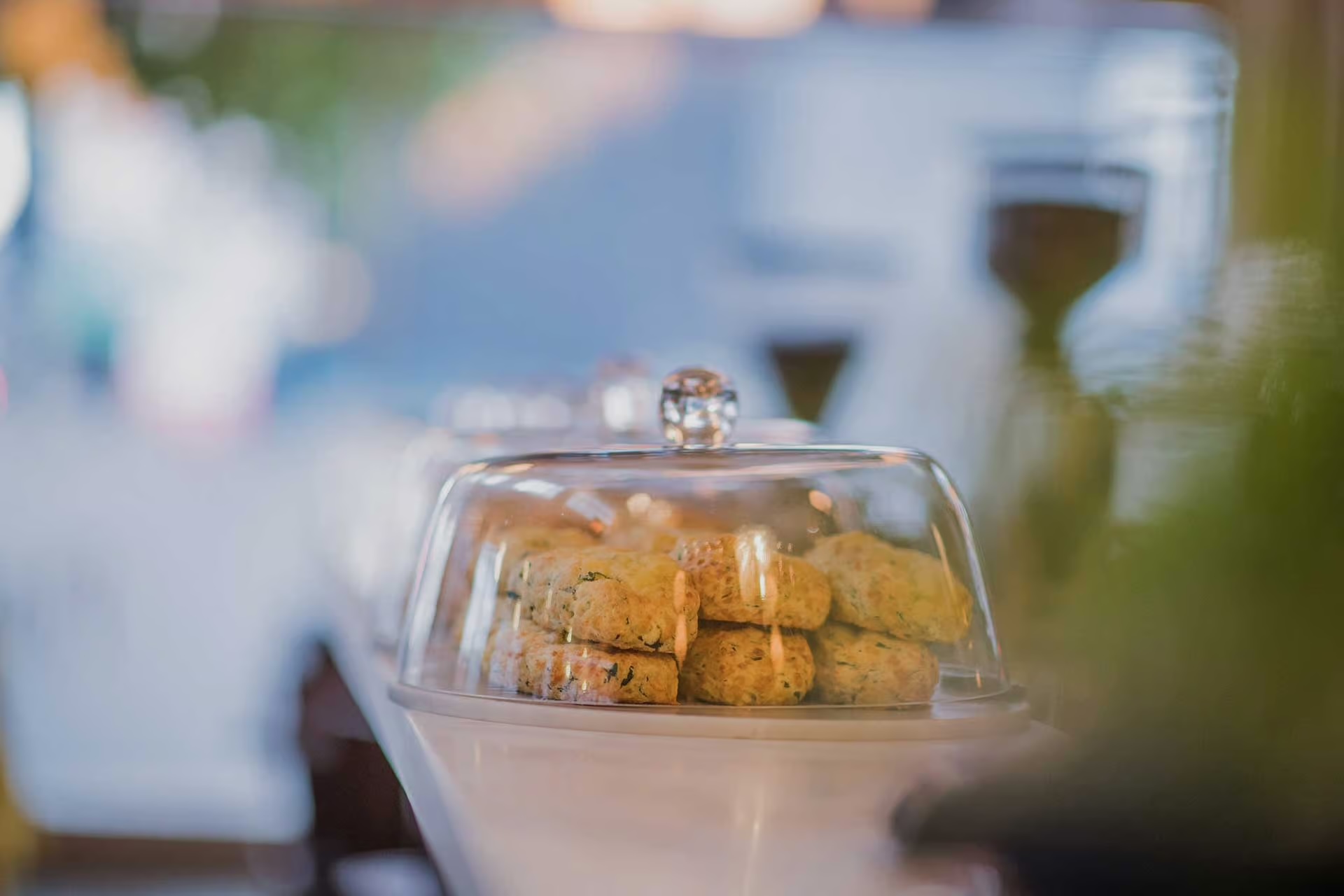 Freshly baked scones stacked under a clear glass cloche on a white countertop.
