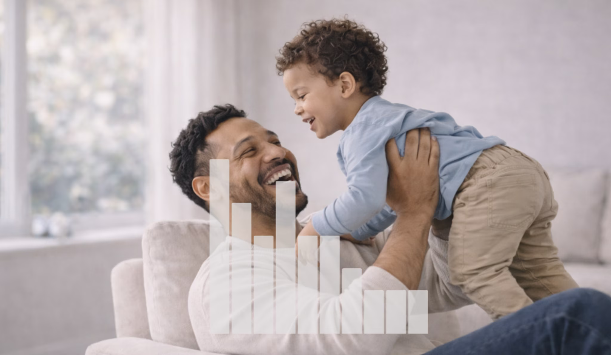 Smiling father lifting and playing with his young son in a bright living room.