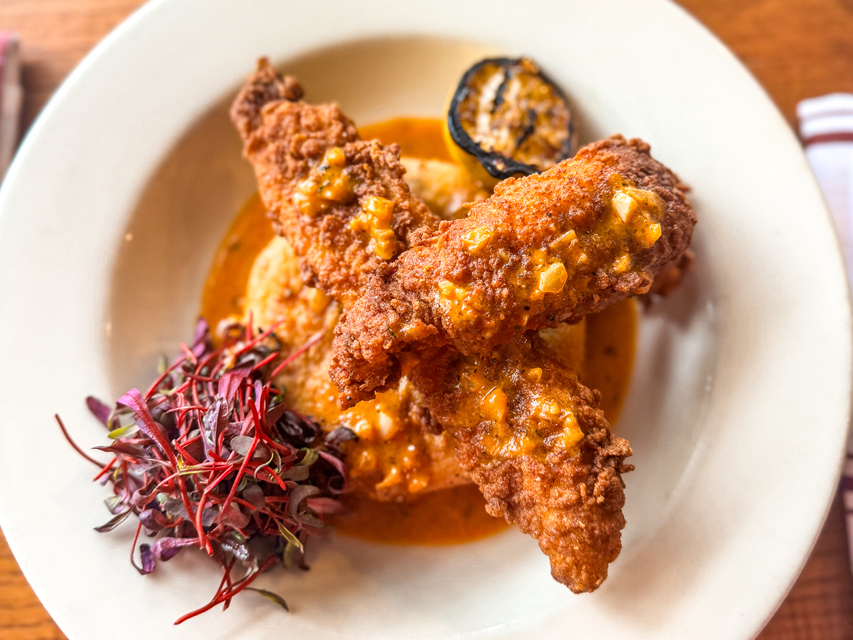 a plate of fried catfish over a grit cake