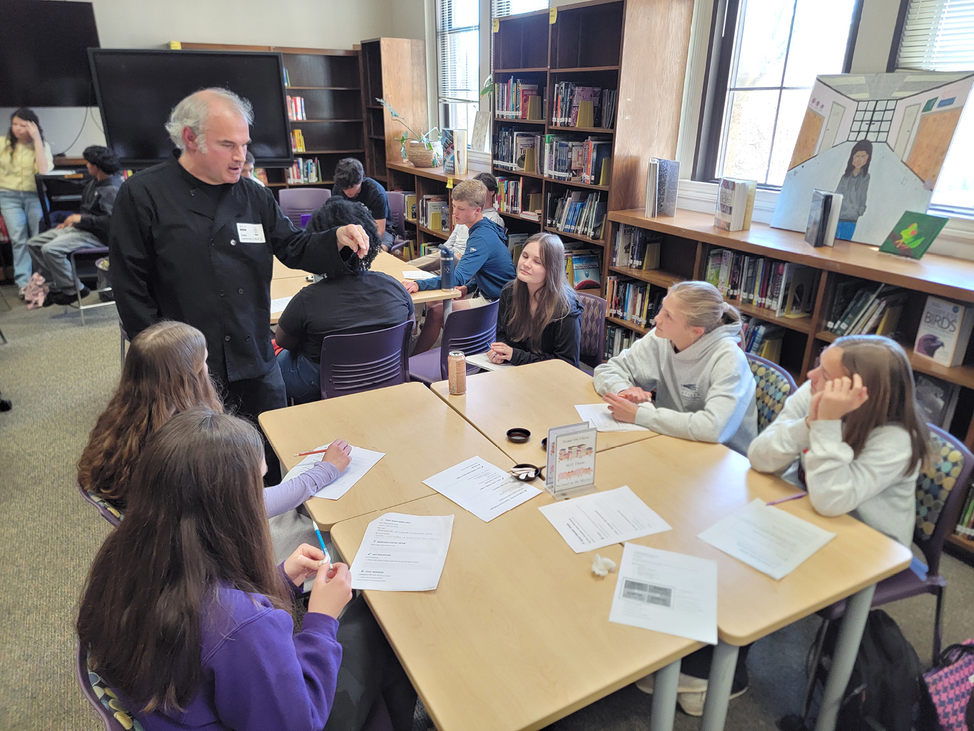 a chef talking to students around tables in a classroom