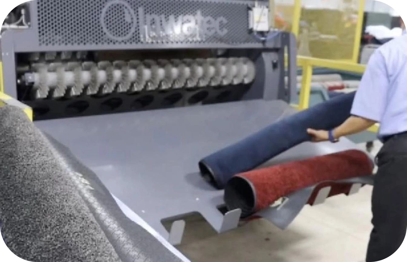 Person handling rolled carpets next to a carpet cleaning machine.
