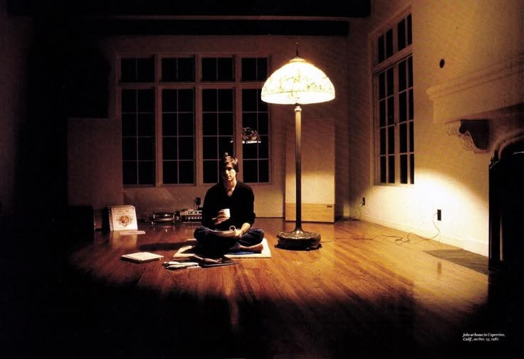 This may contain: a person sitting on the floor in front of a lamp