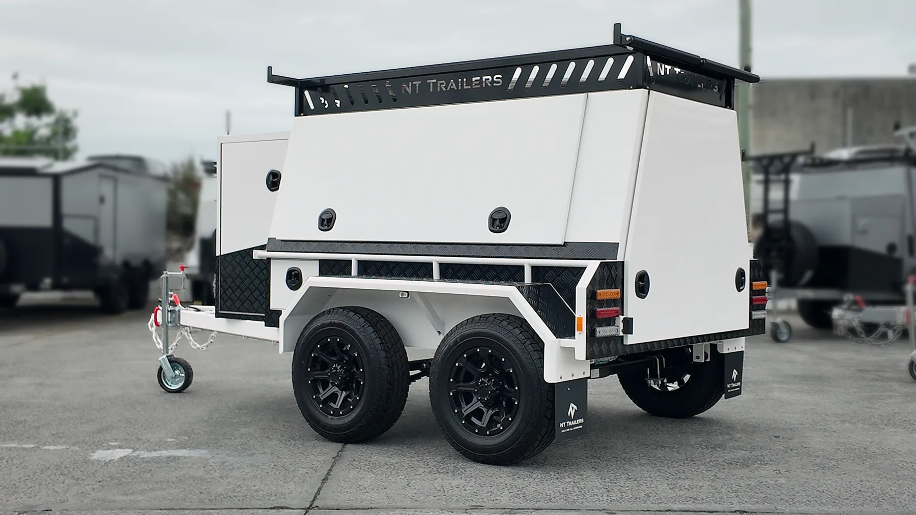 White Essential Builders trailer with black builders rack in the New Tech Trailers yard