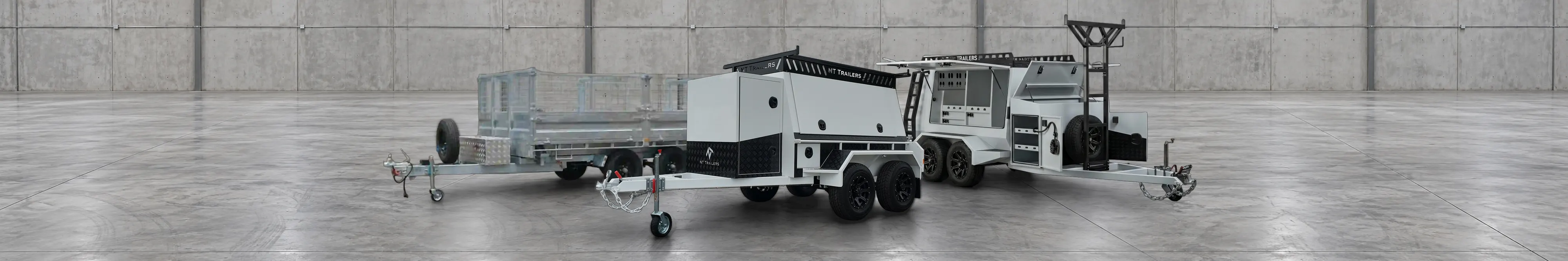 New Tech Trailers hydraulic tipper, Essential Builders and Tradesman trailers side by side in a warehouse
