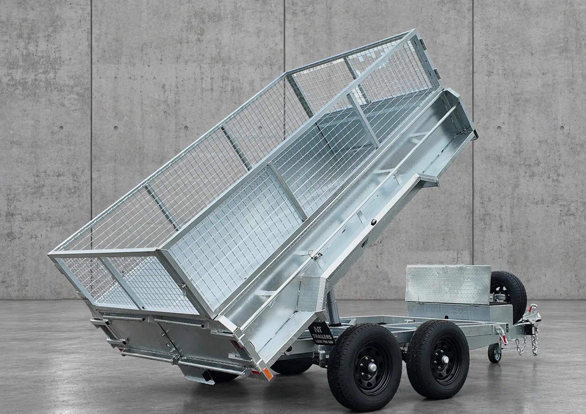 New Tech Trailers 10x6 hydraulic tipper trailer with the cage tub raised, rear three-quarter view