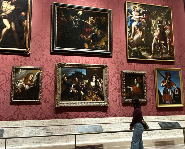 Girl looking at museum wall of artwork.