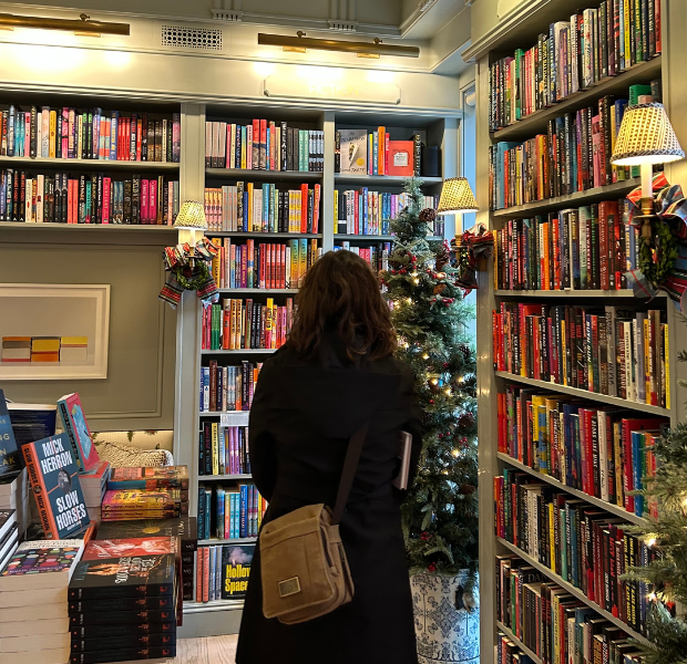 Girl standing in front of shelves of books.