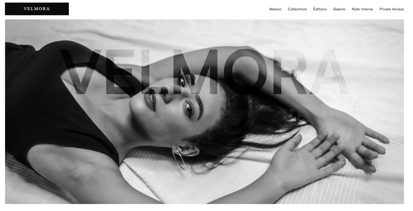 Black and white editorial portrait of a woman lying down, representing the refined and minimal aesthetic of the Velmora brand.
