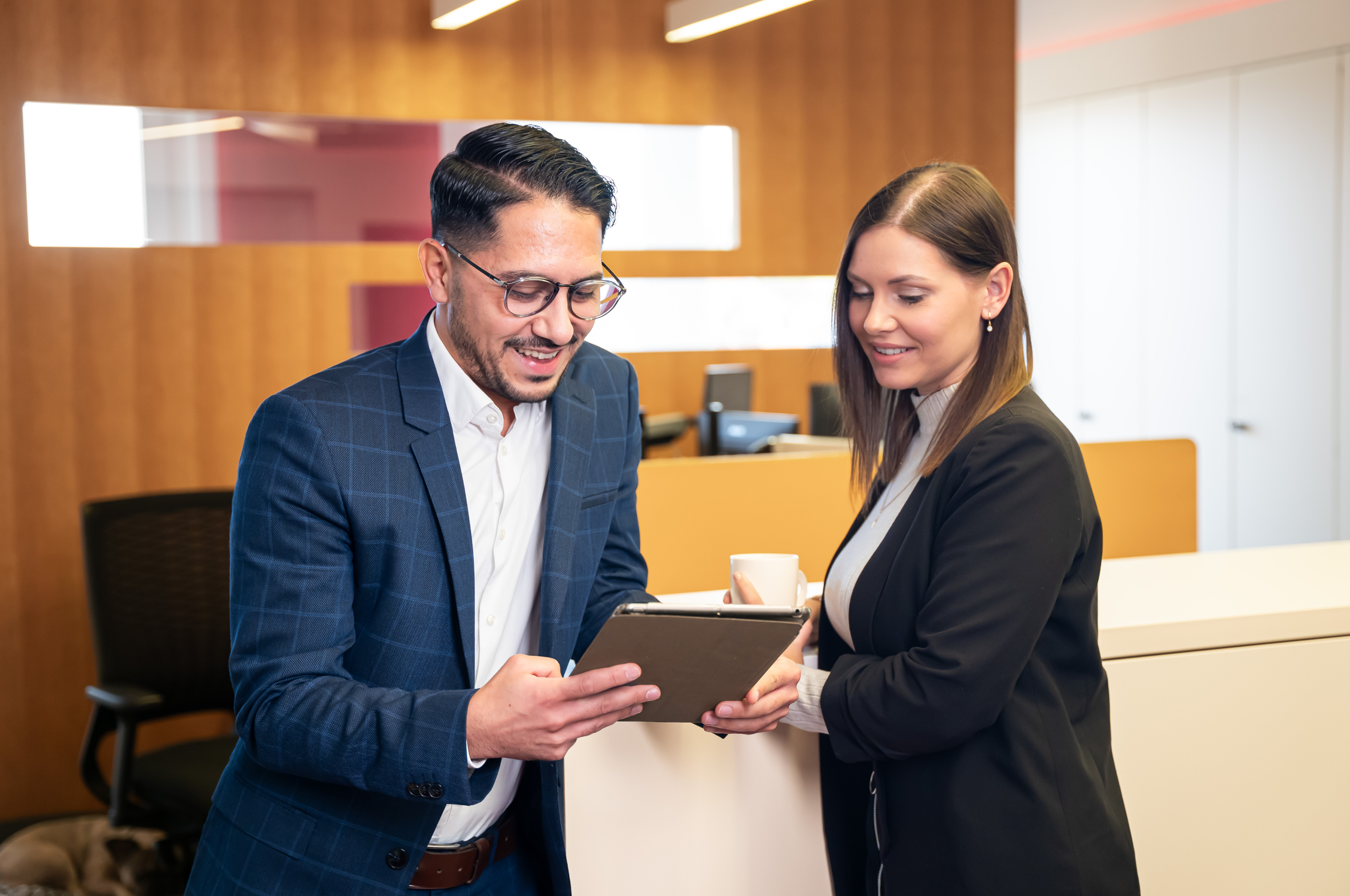 Zwei Personen stehen im Büro und schauen gemeinsam auf ein Tablet.