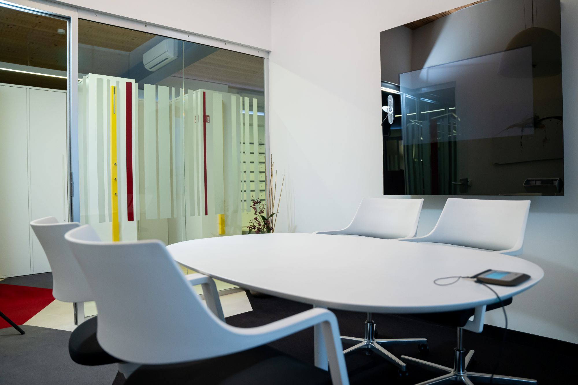 Besprechungsraum mit Tisch, Stühlen und großem Bildschirm an der Wand.