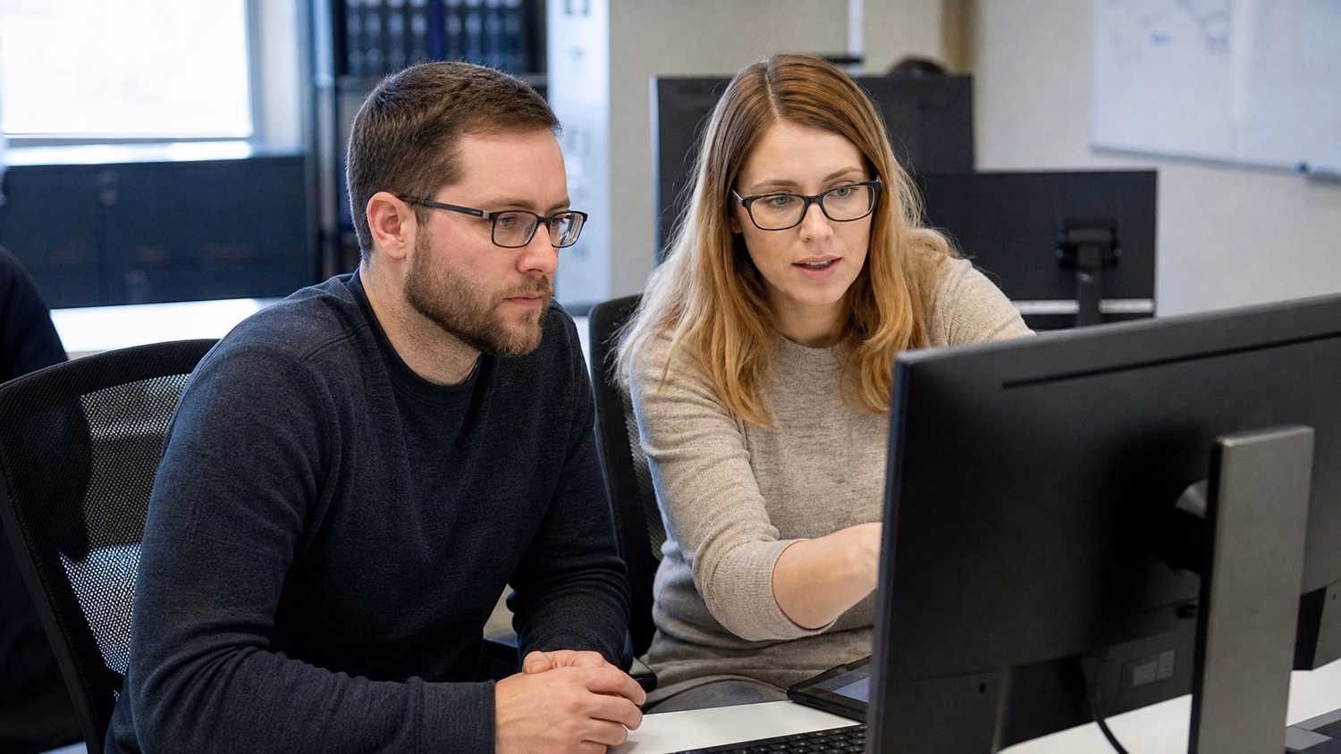 SIDE-BY-SIDE PAIR An IT professional two people seated side by side reviewin