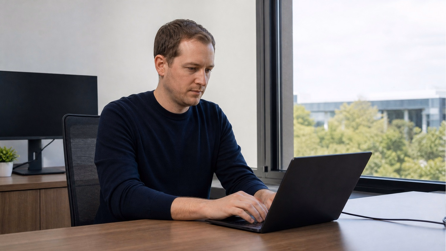 WINDOW SEAT LAPTOP An IT professional one person working on a laptop at a de