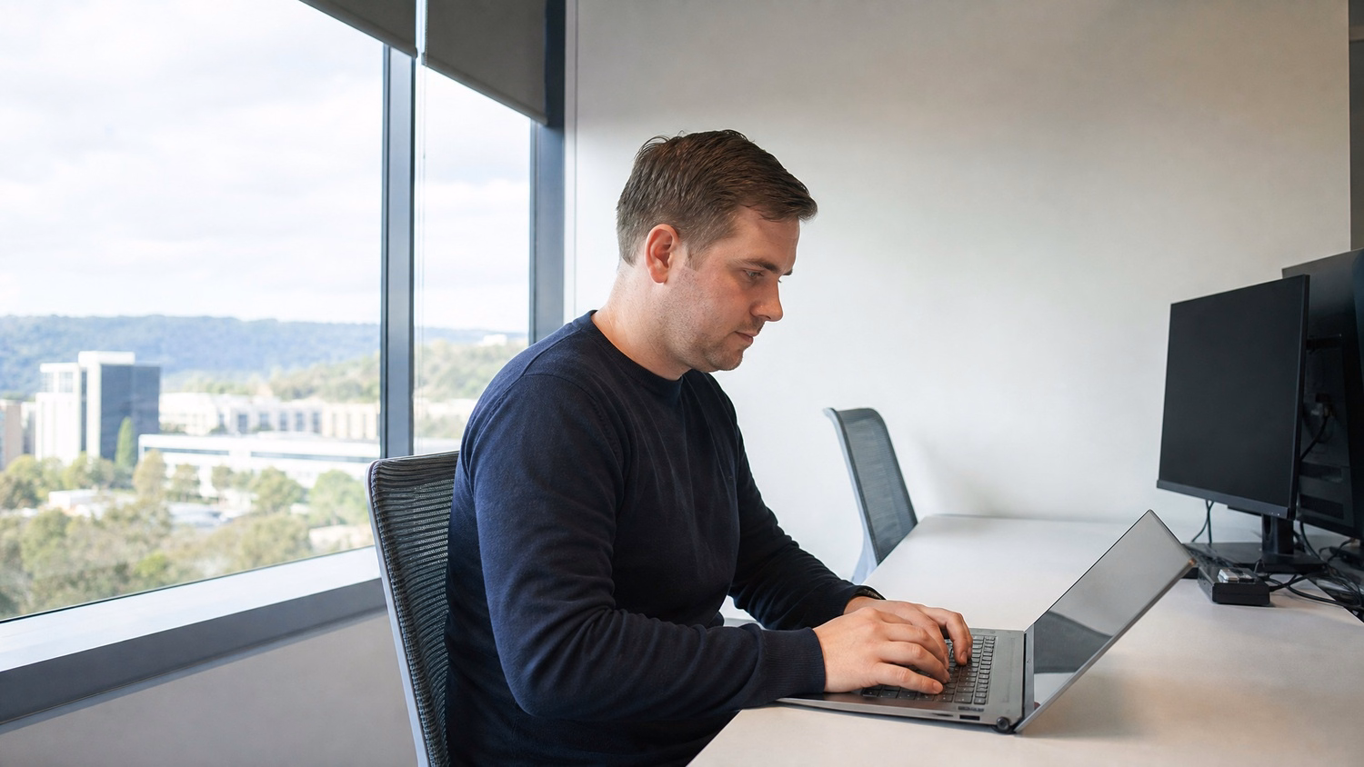 WINDOW SEAT LAPTOP An IT professional one person working on a laptop at a de