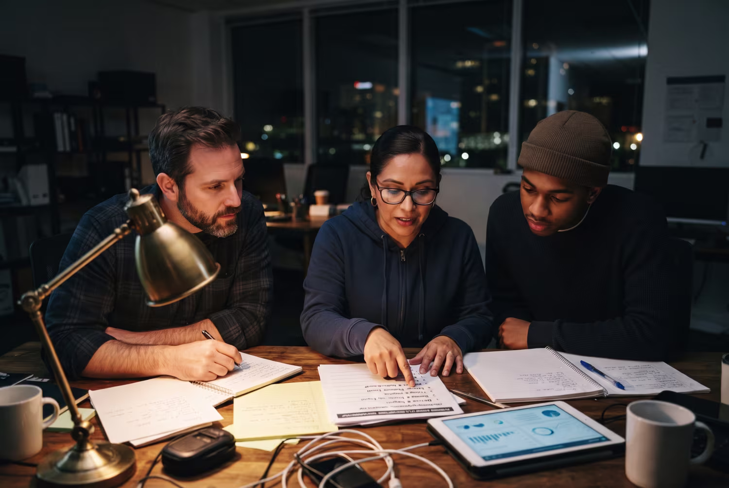 Three IT employees discussing security awareness training topics in dimly lit office